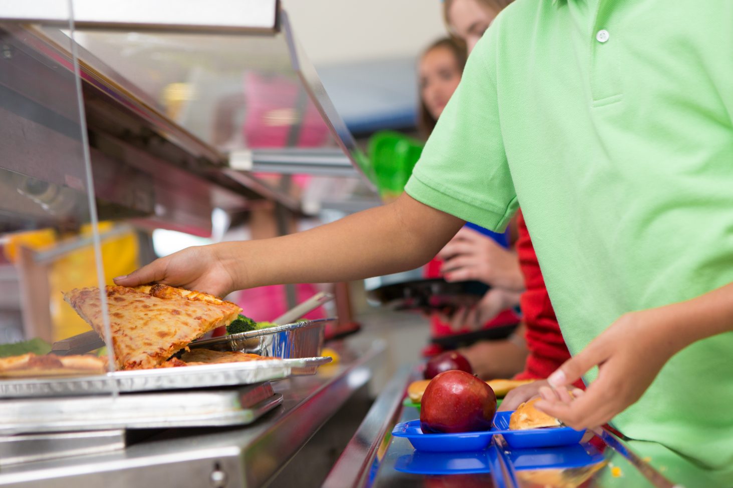 Boy choosing piece of pizza in the school lunch line